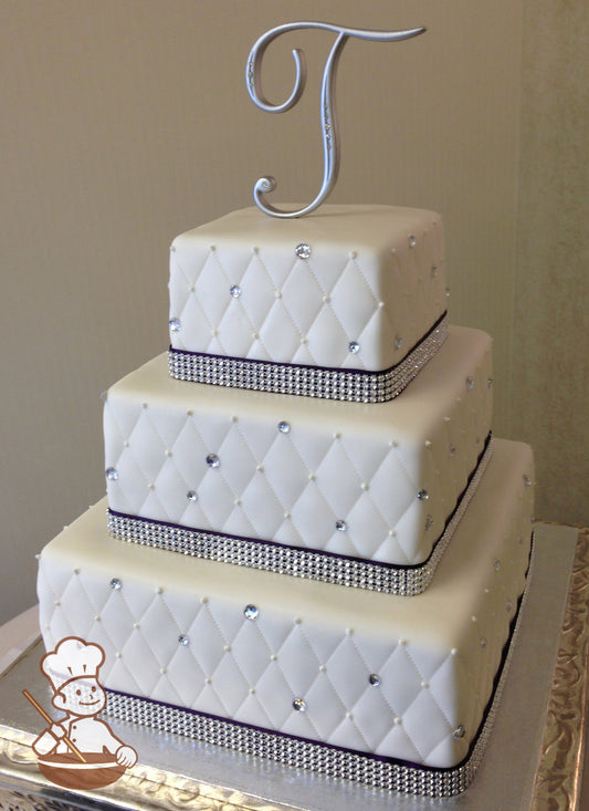 Square fondant wedding cake with quilted pattern with rhinestone and bead design.  Bottom of each tier is wrapped with rhinestone bands.