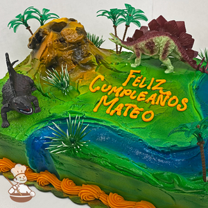 Birthday sheet cake with dinosaur toy sets and buttercream volcano and river running through the jungle.