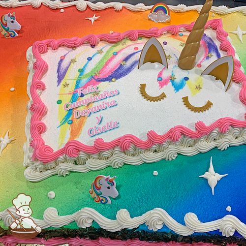 Birthday sheet cake with unicorn toy set on photo layer with sprayed rainbow and unicorn rings.
